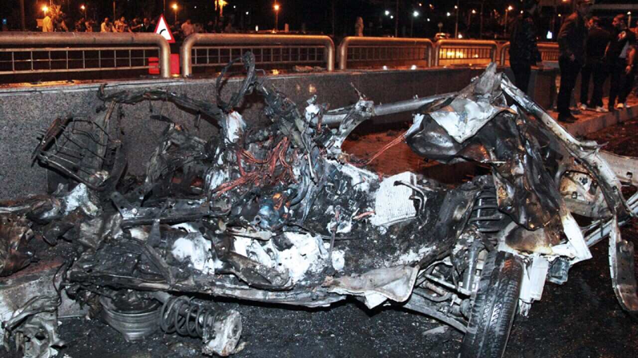 Syrian policemen inspect the site of a suicide car bomb