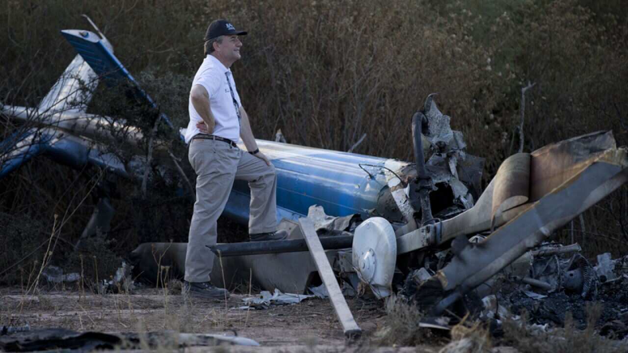 A civil aviation investigator with wreckage of a helicopter