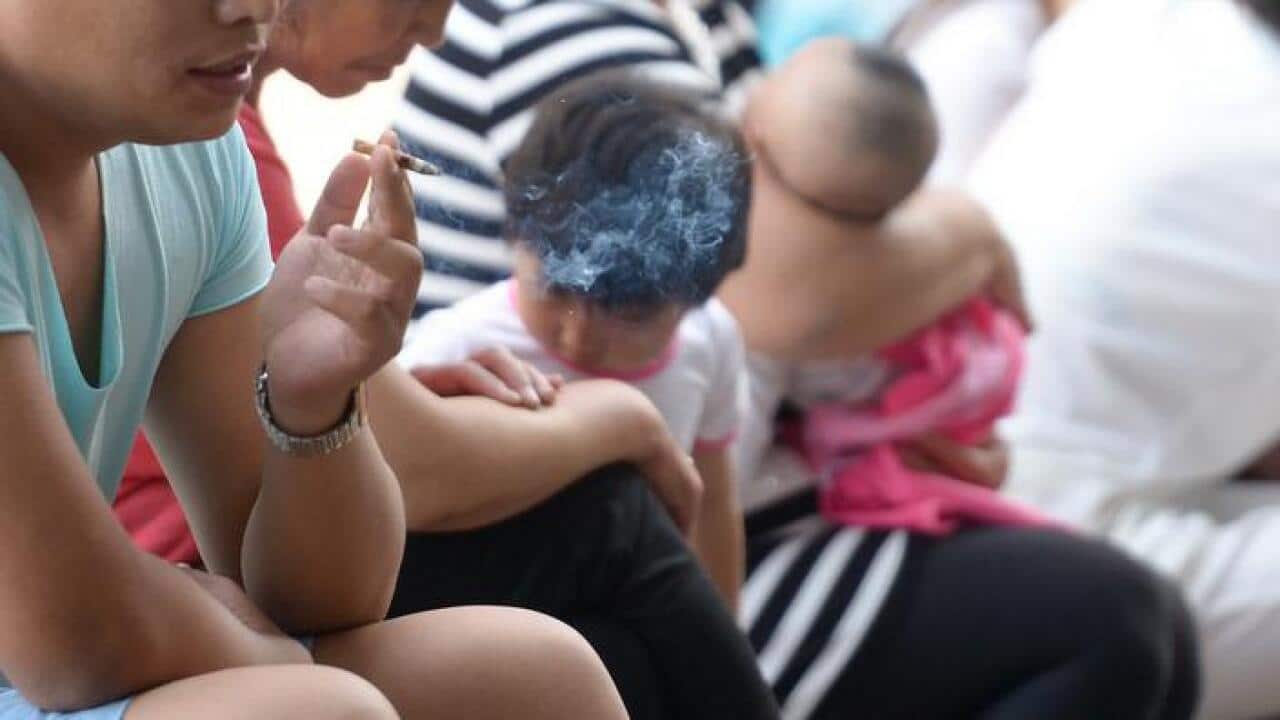 A man smokes next to children at the Beijing Children's Hospital in Beijing, China (AAP)