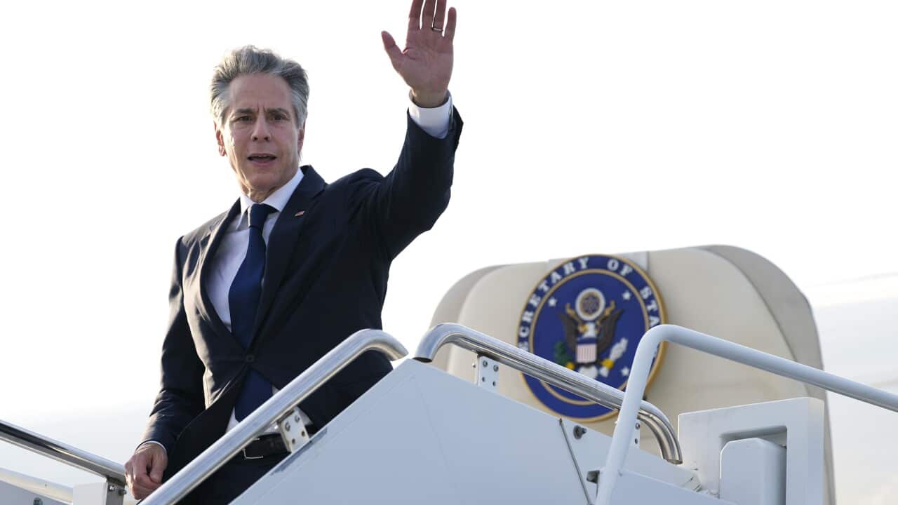 A man in a suit waving as he boards a plane.