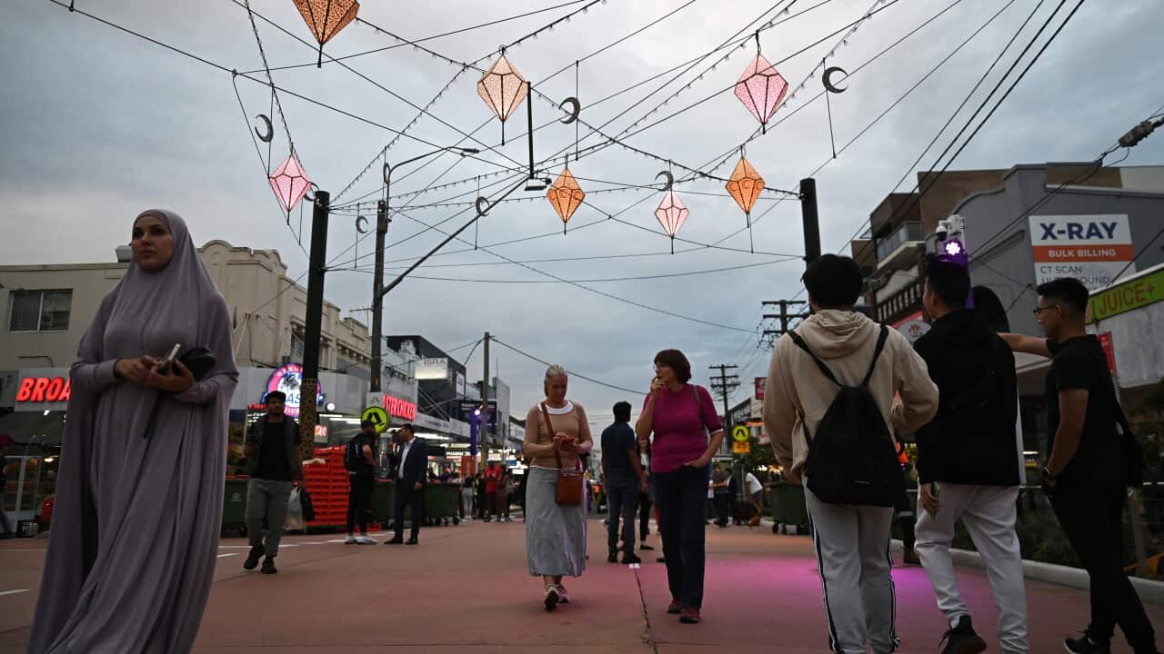 People walk through a street with decorations hung up.