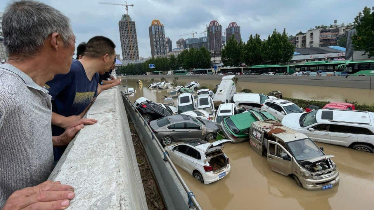 People look out at cars sitting in floodwaters after heavy rains hit the city of Zhengzhou in China's central Henan province on July 21, 2021