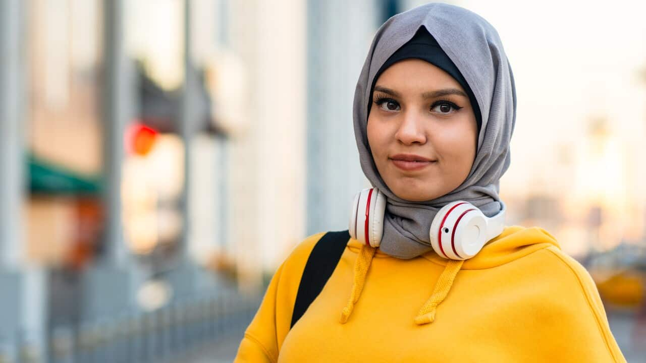 Stock photo of a young woman wearing a headscarf and holding a coffee cup