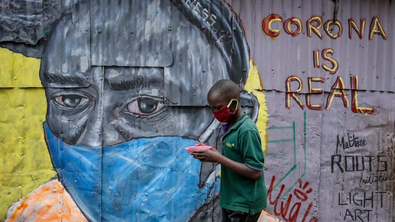 A boy wearing a face mask walks past an informational mural warning people about the risk of the new coronavirus in the Mathare slum of Nairobi, Kenya.