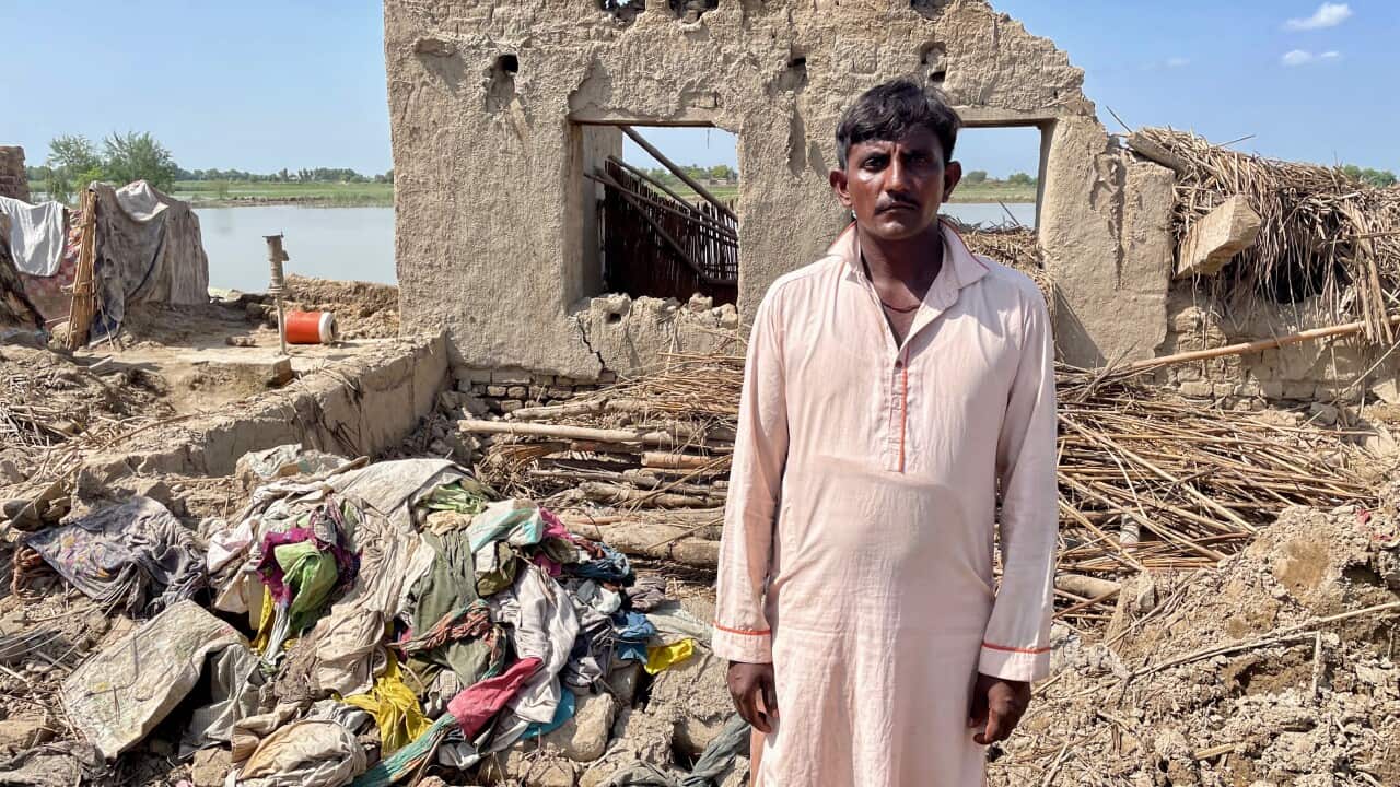 Imam Din stands in front of the rubble of his brother's home.jpg