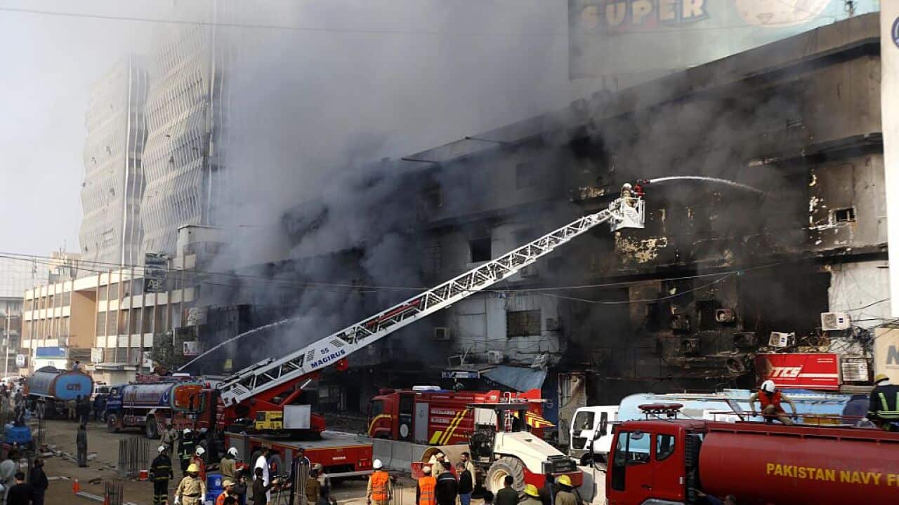 Firefighters work to contain a fire in a scorched building.