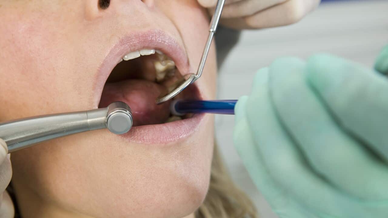 Close-up of a dentist inspecting a woman's mouth
