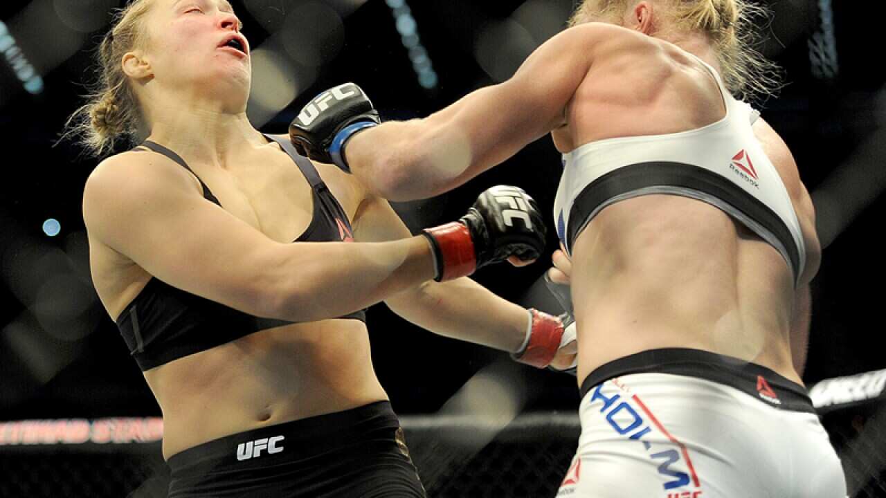 Holly Holm (R) strikes Ronda Rousey