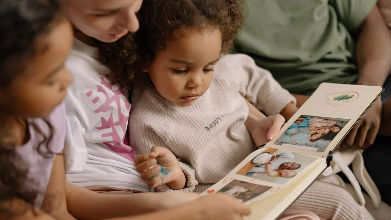 Mother with Daughters Looking at a Photo Album