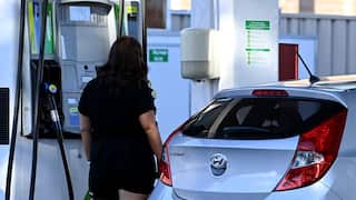 A woman at a petrol pump filling her car with petrol.