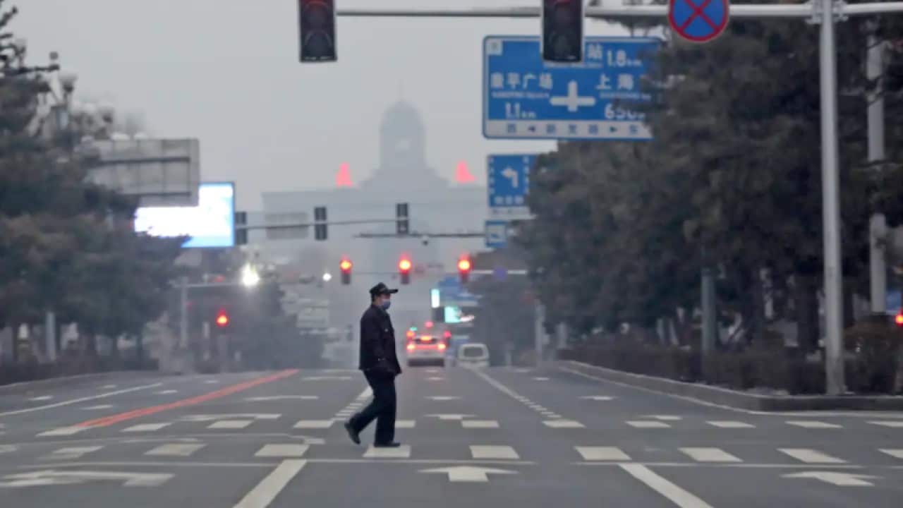 A man walks across an empty road during the fourth day of a city-wide lockdown in Changchun in northeastern China's Jilin province on Monday