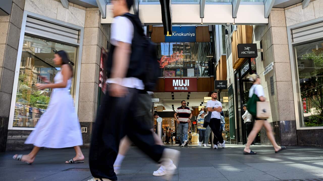 An image of a person's blurred outline walking past a  shopping centre