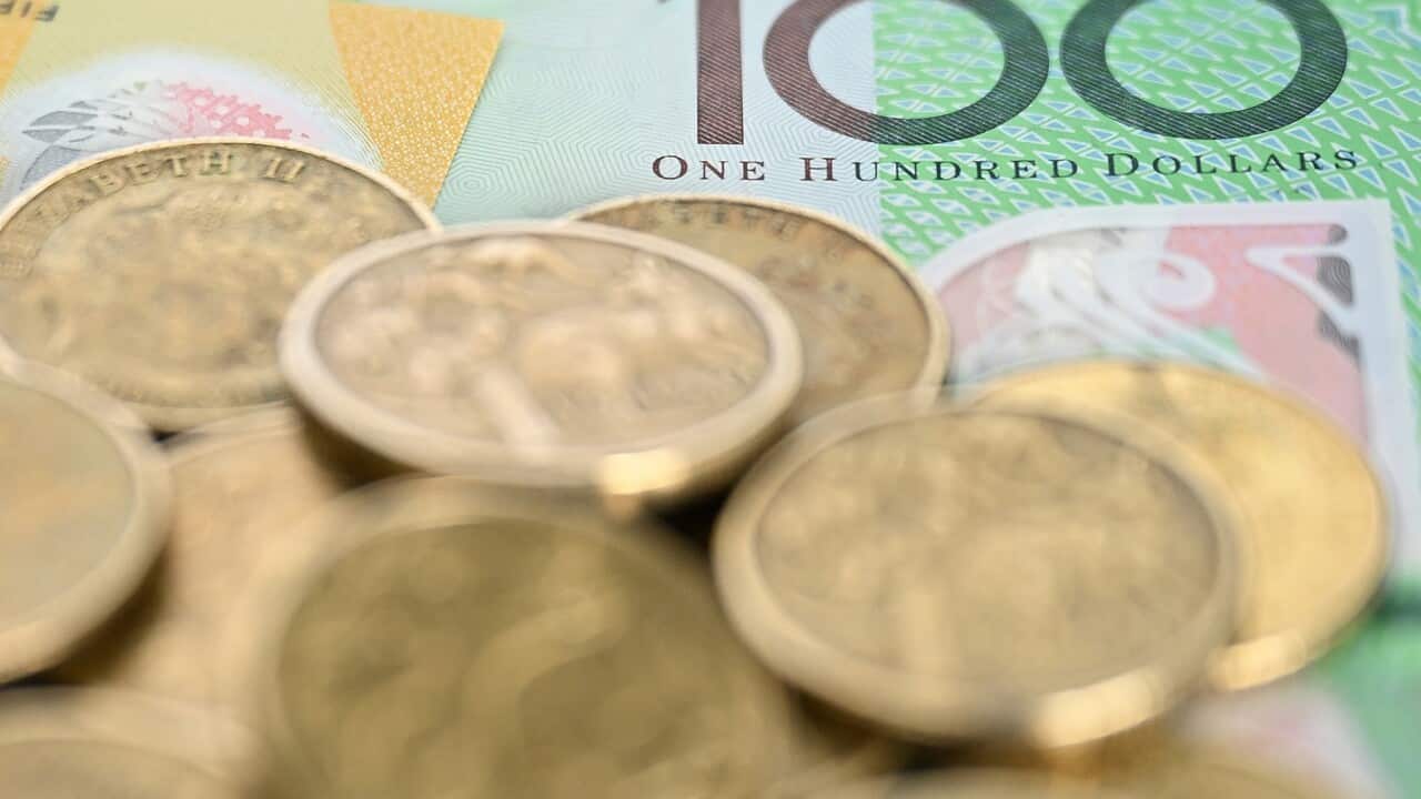 A pile of Australian one dollar coins on top of a $100 note.
