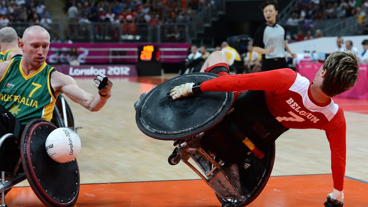 Two men in wheelchairs playing rugby on a court.