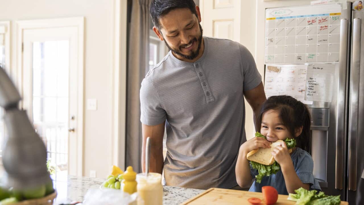 Father and daughter making sandwich in kitchen