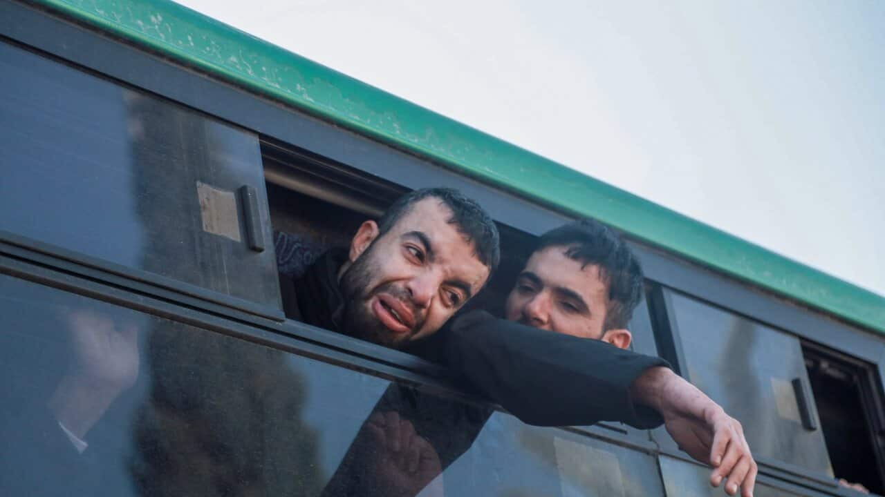 Two men with their heads out of a bus window.