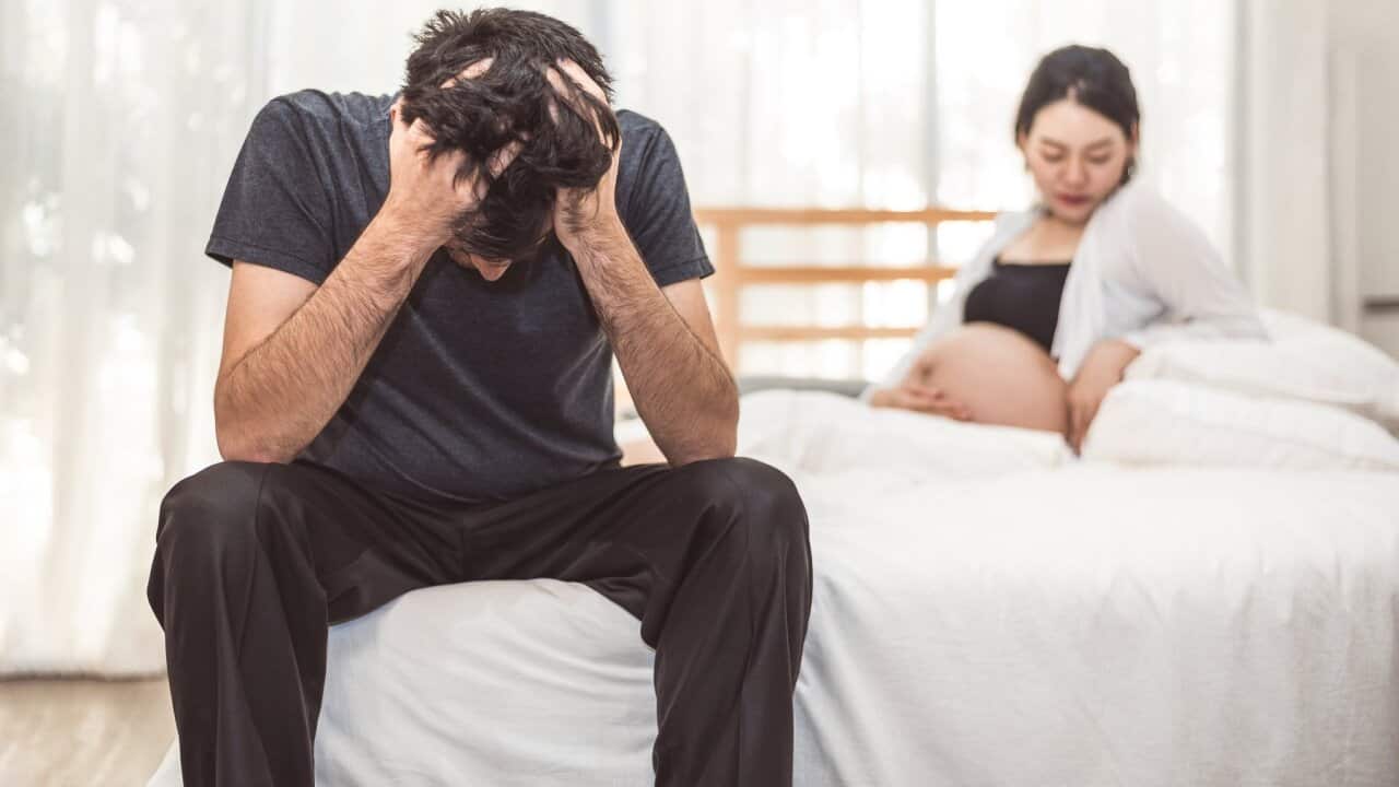 Young Couple Sitting On Bed At Home