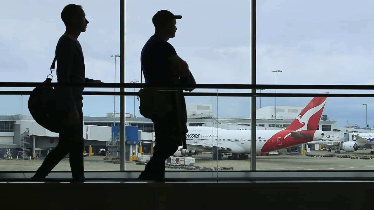 Two people hugging in an airport arrivals section.