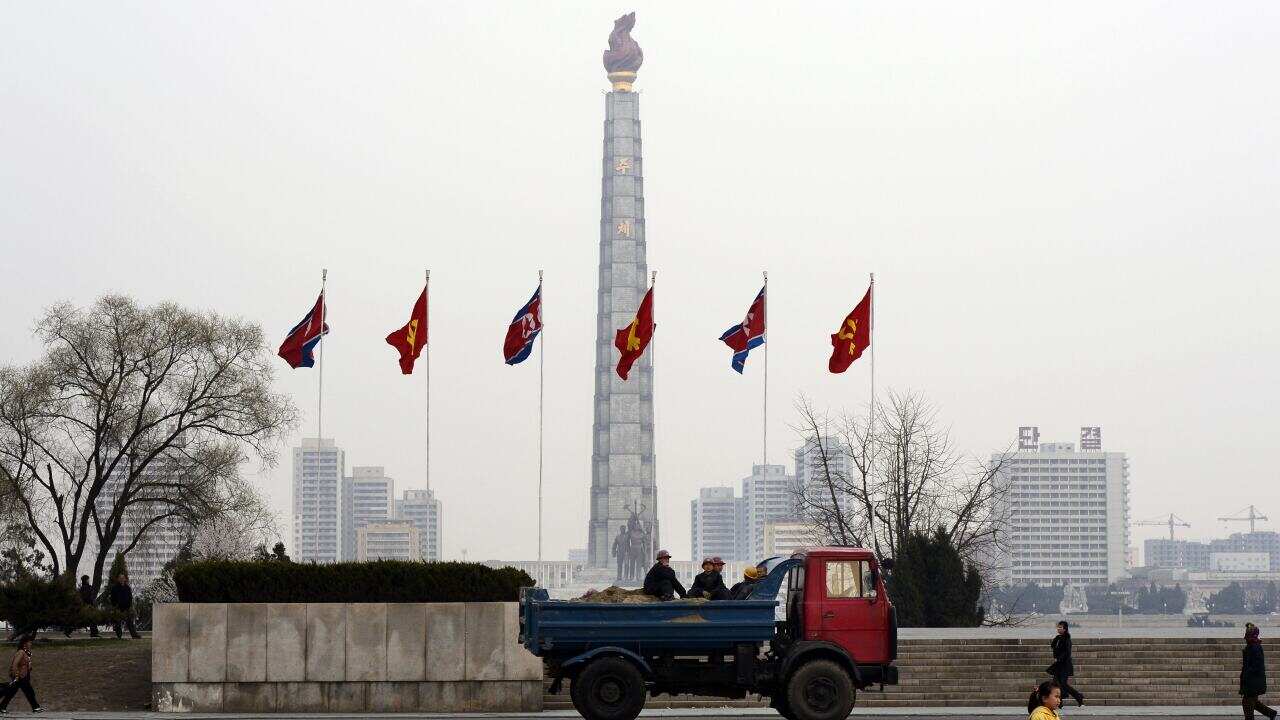 A truck transporting workers drives past the Juche tower monument in Pyongyang