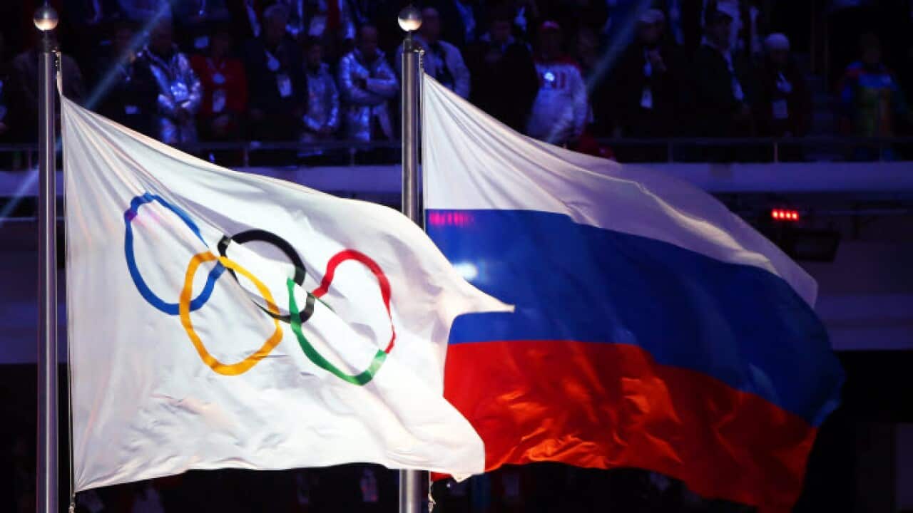 he Olympic flag (L) and the Russian flag (R) fly