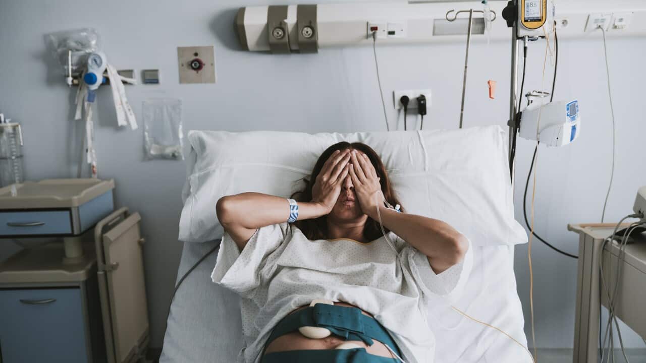 Stressed pregnant woman lying on bed in hospital