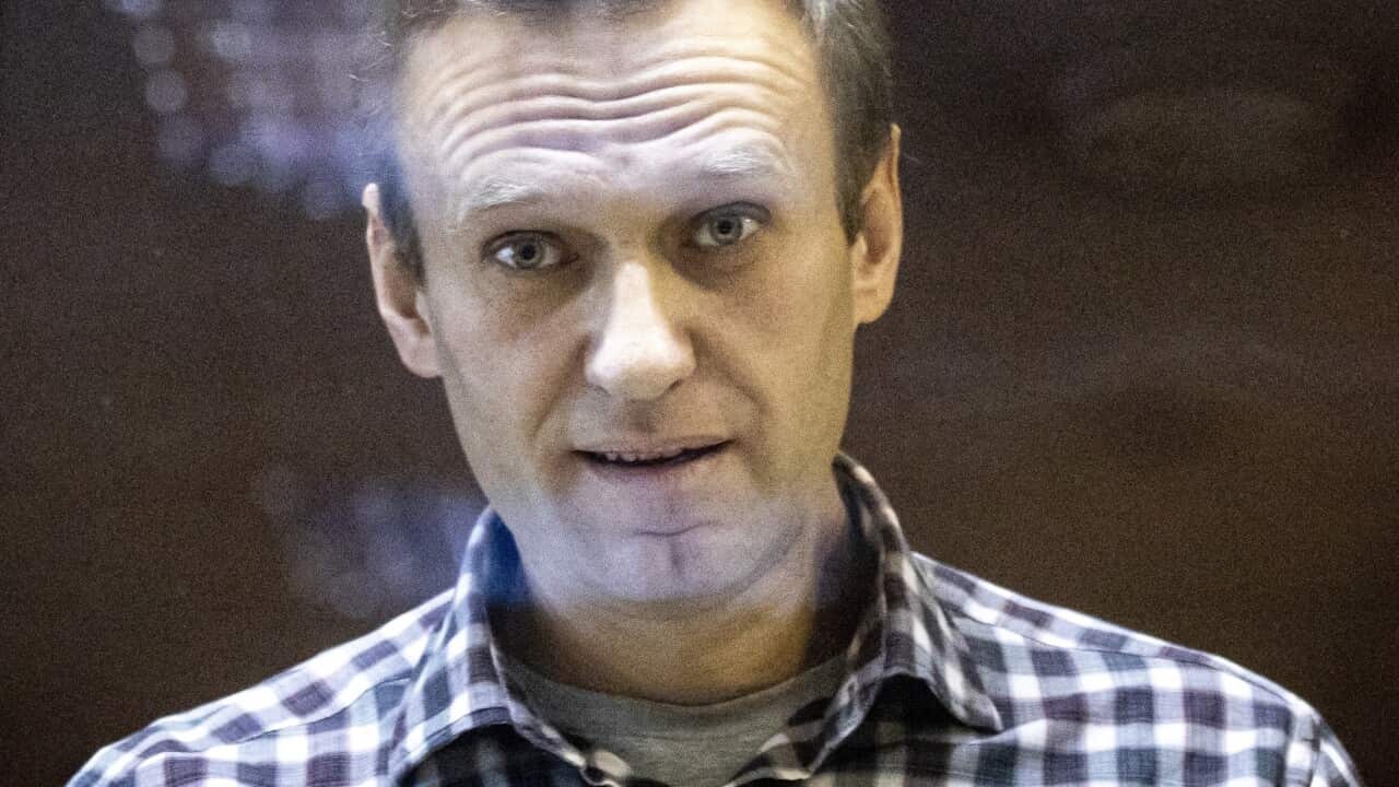 A man inside a glass cage in a courtroom