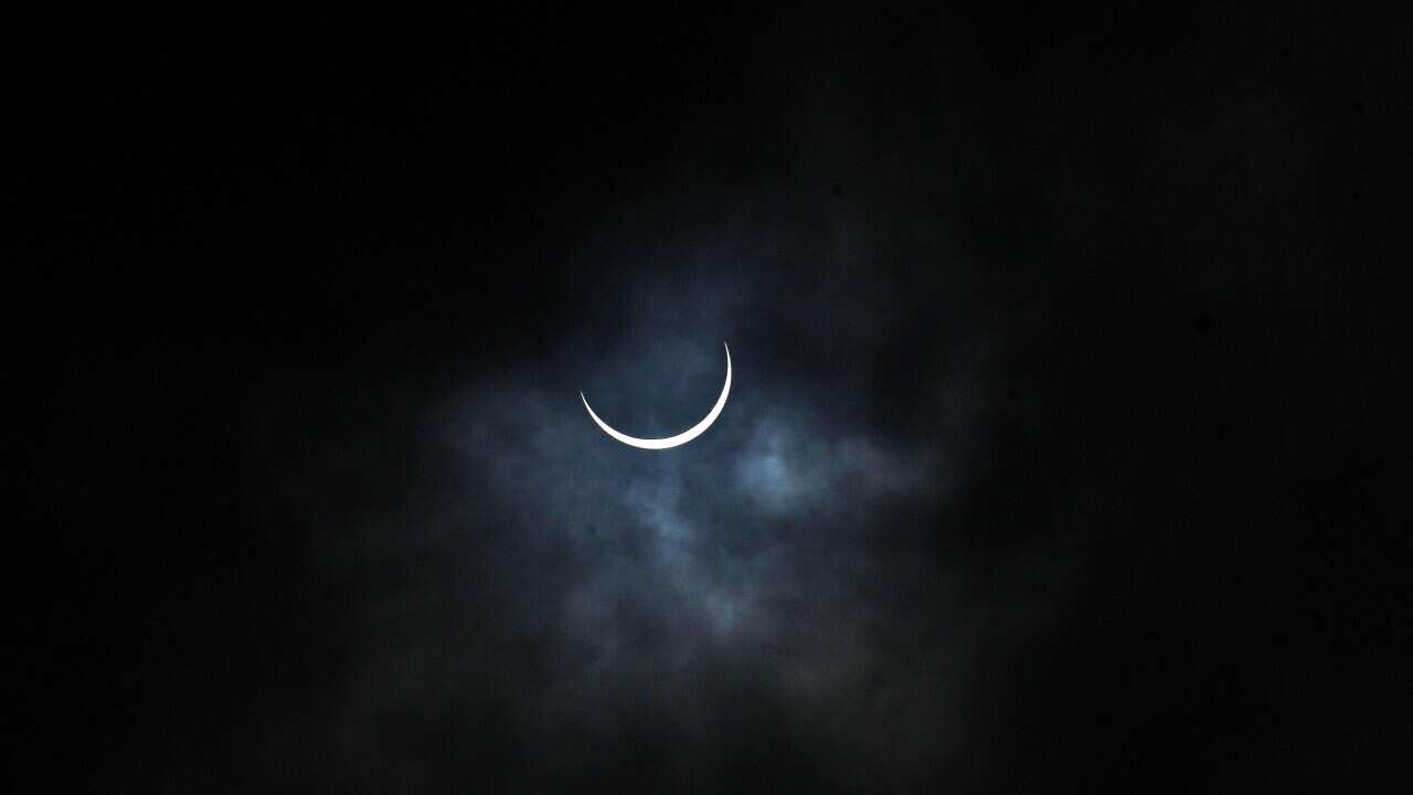 The partially eclipsed sun seen in an overcast sky in New Delhi