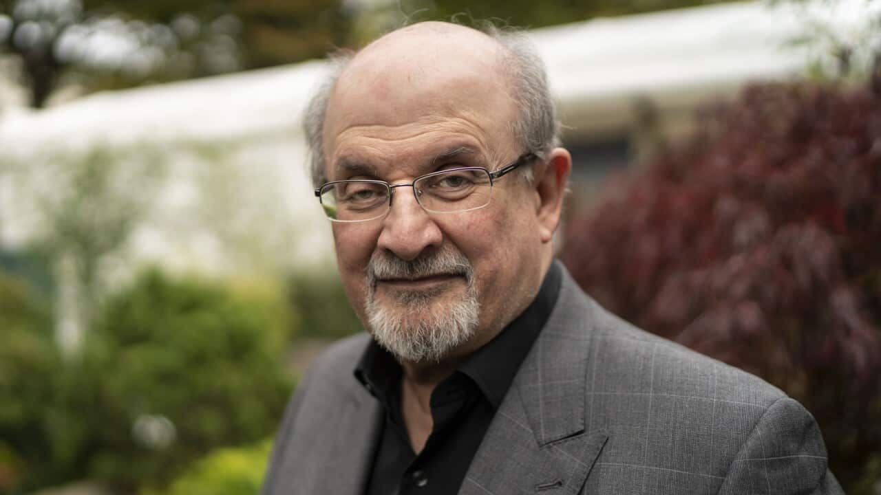Portrait of Salman Rushdie smiling warmly in a grey blazer.