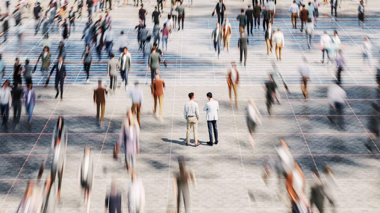 Businessmen on the street standing in crowds of walking people