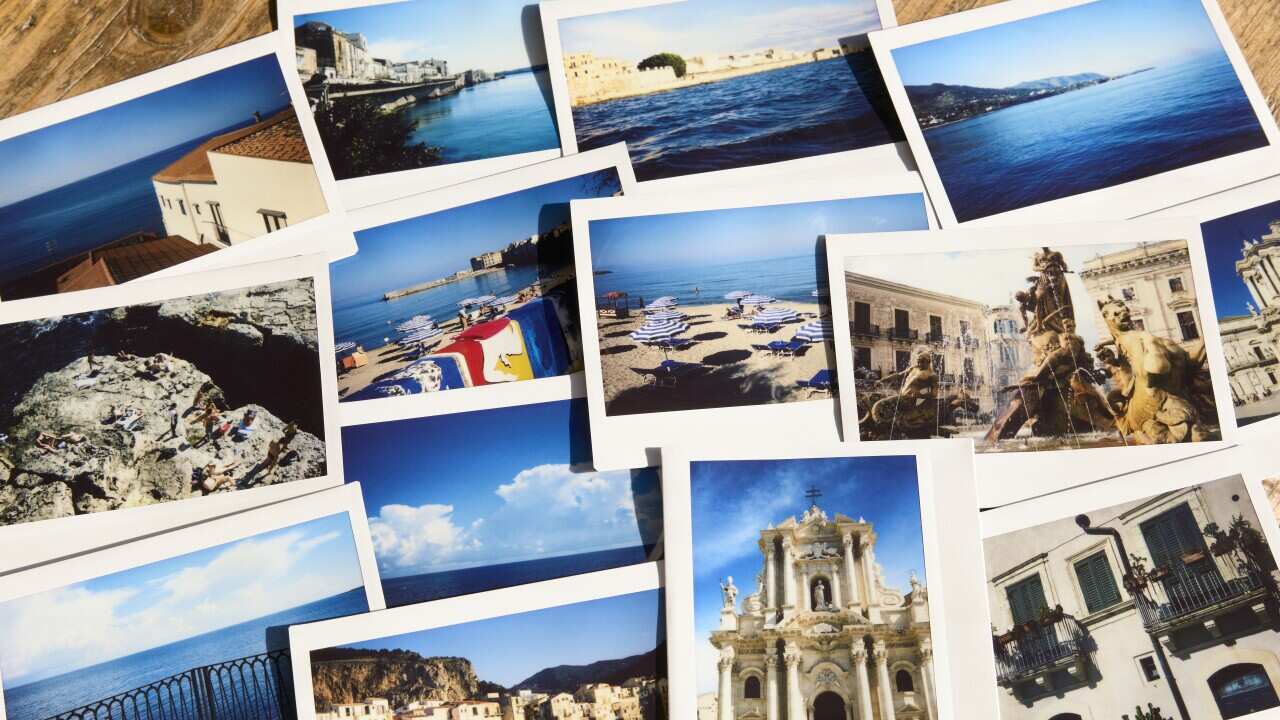Assortment of instant travel holiday photos from Sicily on a table