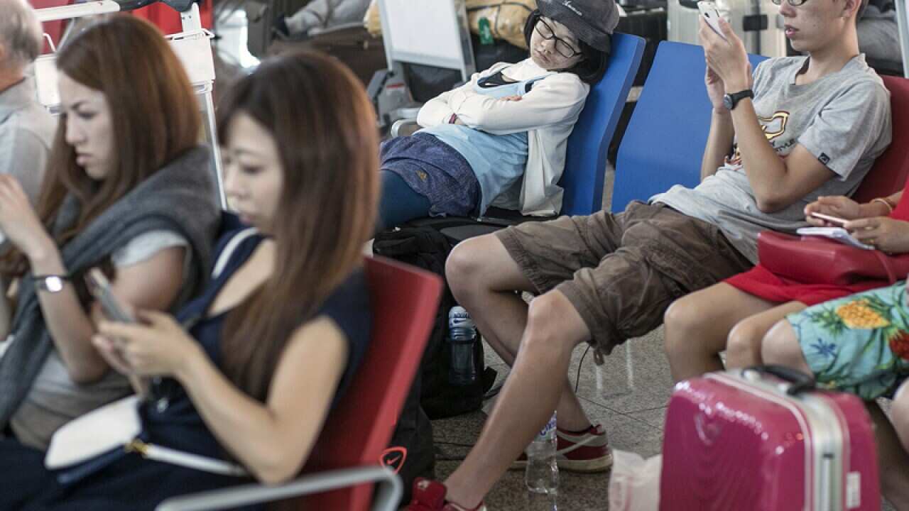 Tourists wait at Denpasar Airport