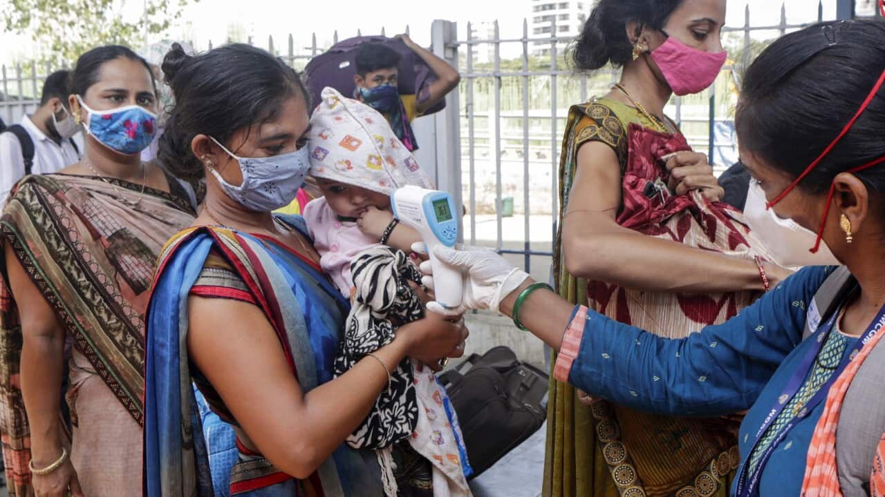 A health worker screens travellers at a train station in Mumbai, India on 24 May 2020. 