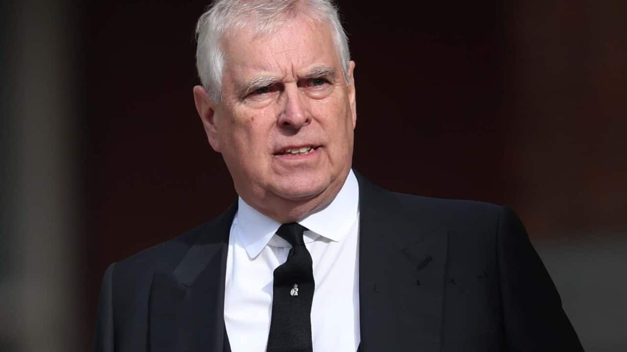 Prince Andrew wearing a black suit with a stern look on his face.