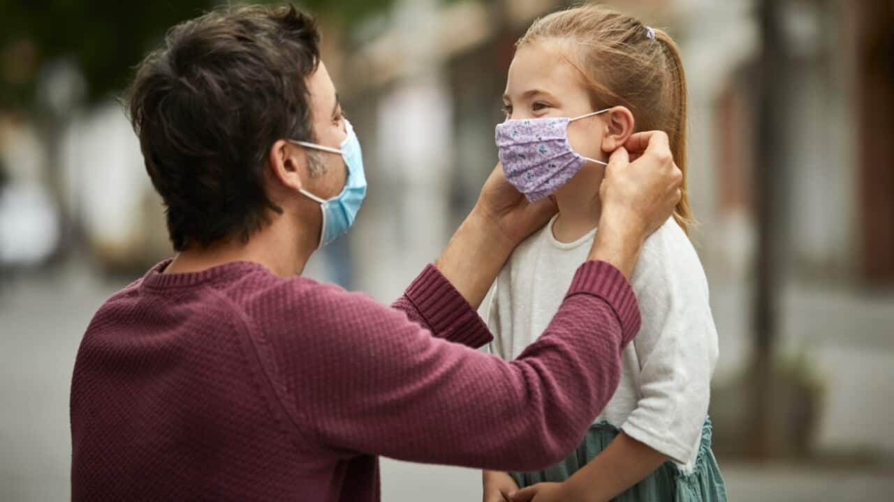 Father helps daughter with mask - Getty Images - Morsa