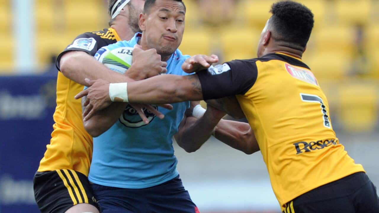 Waratahs' Israel Folau (C) is wrapped up by the Hurricanes