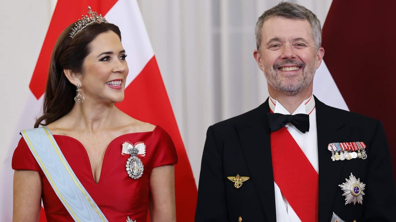 A woman with a crown standing on the left of a man with a jacket and badges