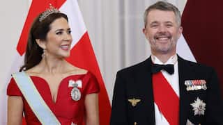 A woman with a crown standing on the left of a man with a jacket and badges