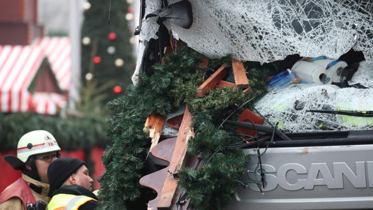 A police officer and fireman inspect a damaged truck in Berlin
