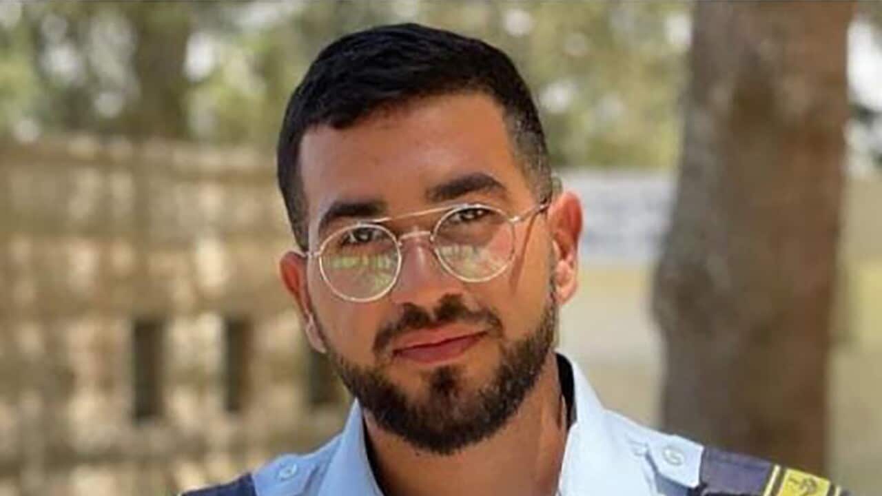 A young man with black hair and glasses wearing a blue uniform