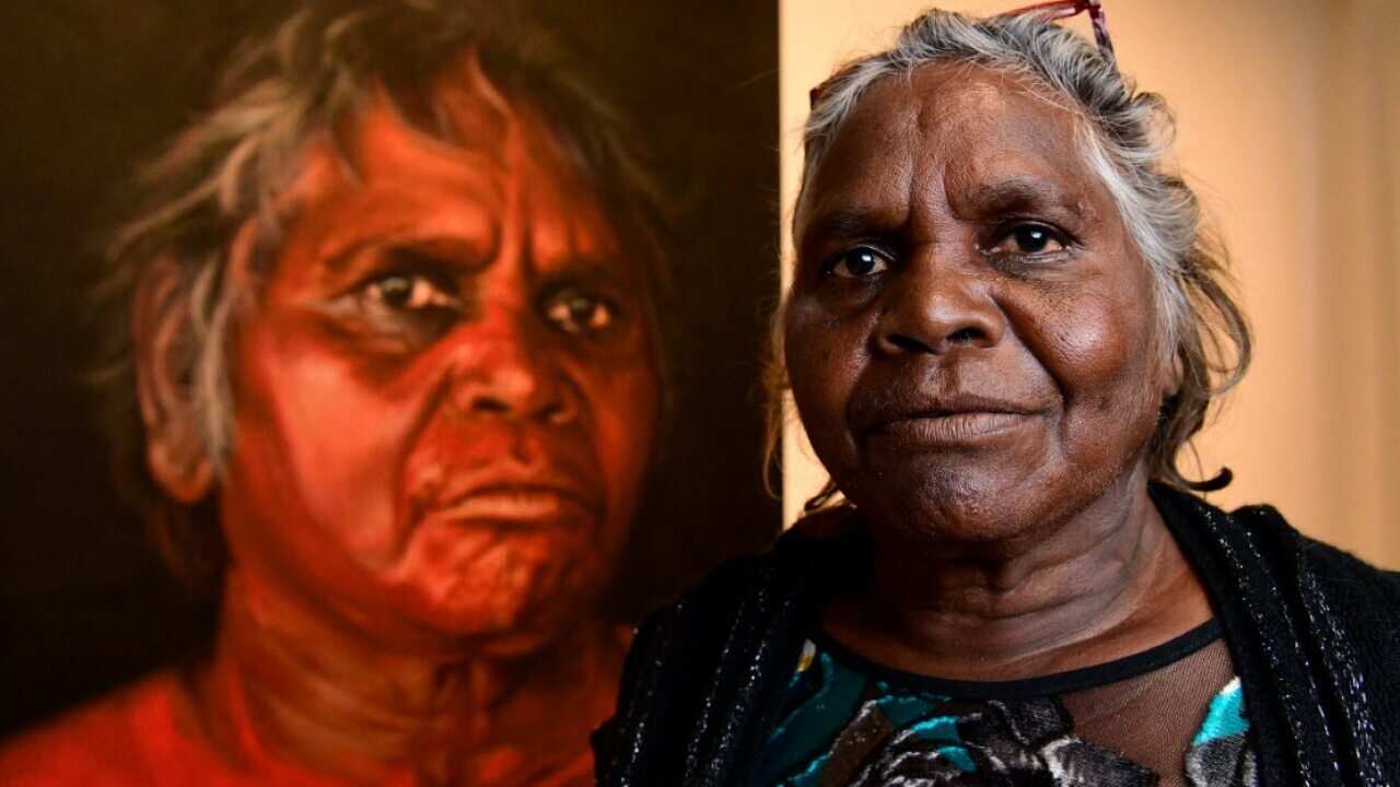 Aboriginal Elder Daisy Tjuparntarri Ward poses for a photograph in front of artist David Darcy's portrait of her at the Art Gallery of NSW in Sydney