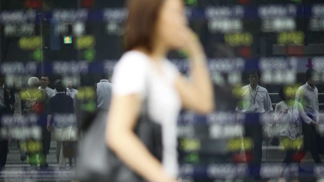 Pedestrians are reflected on an electronic stock board