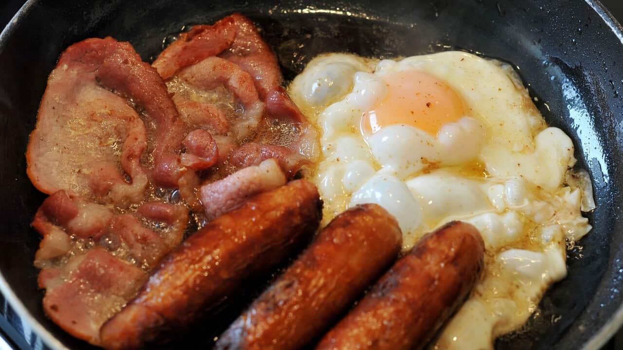Egg, sausages and bacon being fried in a frying pan.