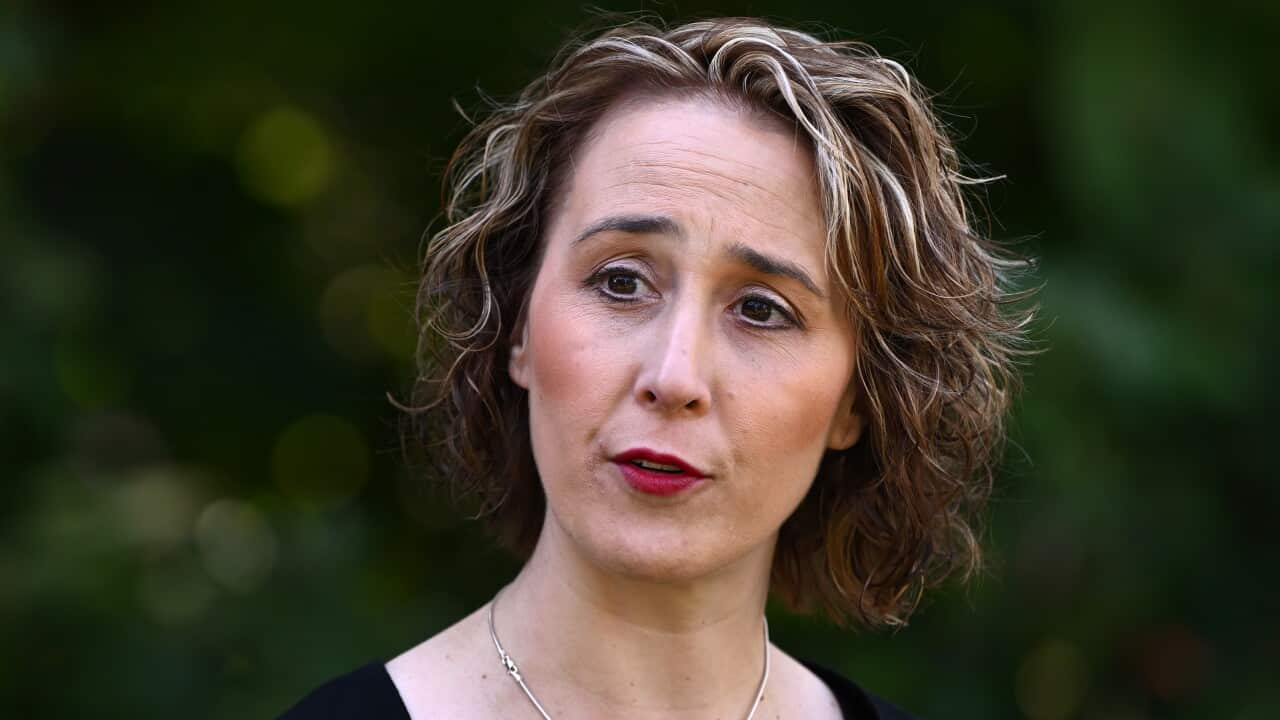 A woman in a black top and silver necklace.