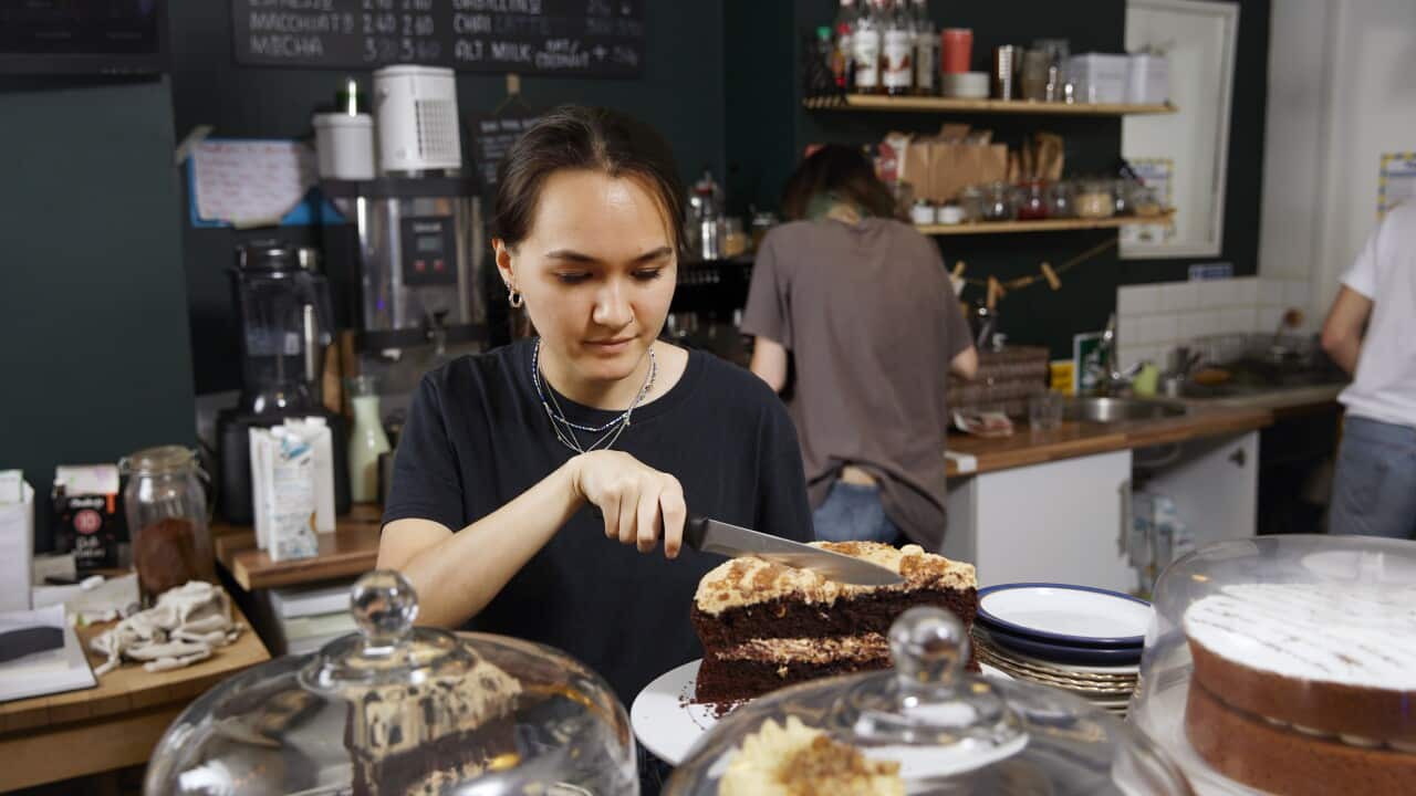 A waitress in a cafe cutting a slice of cake