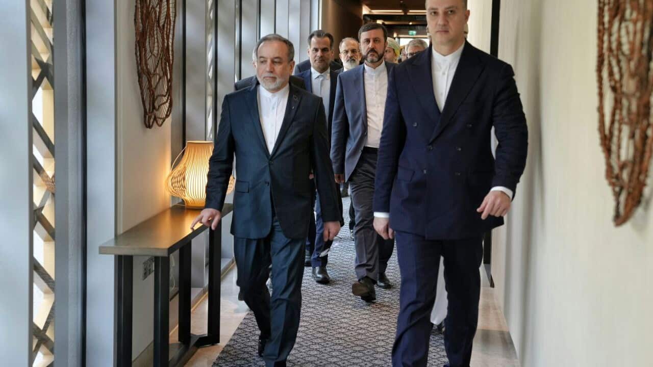 A group of men wearing suites walking through a corridor