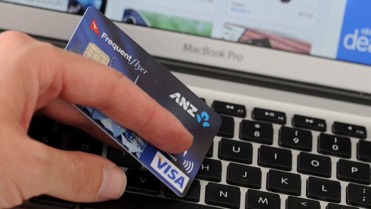 A credit card is held in front of an online shopping site