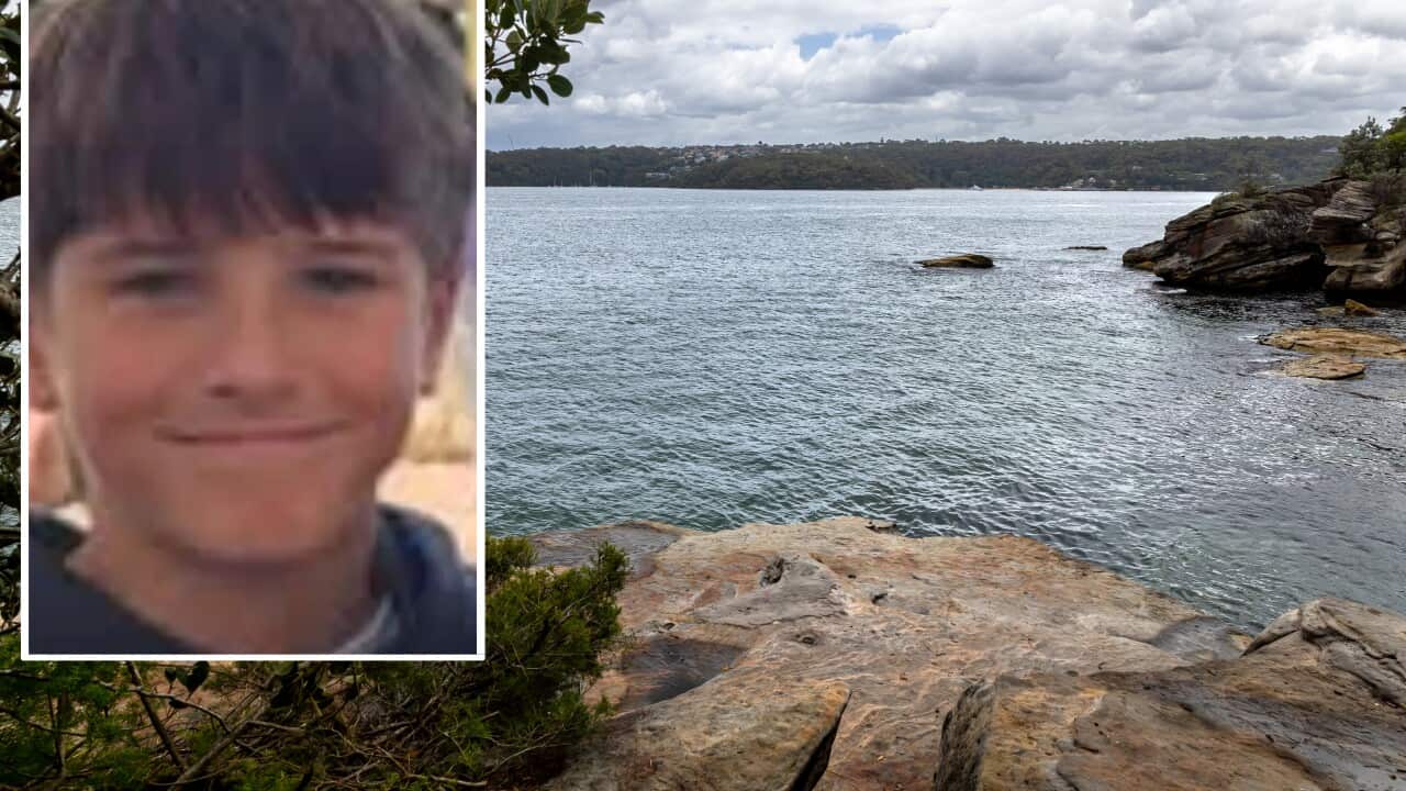 A photo of a boy in a blue shirt set against the background of a rocky beach.