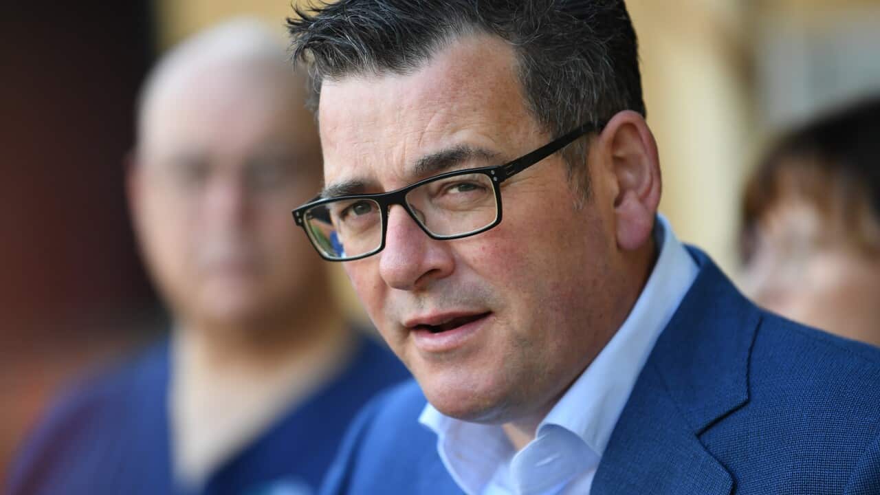 A man wearing a suit and glasses who is speaking.