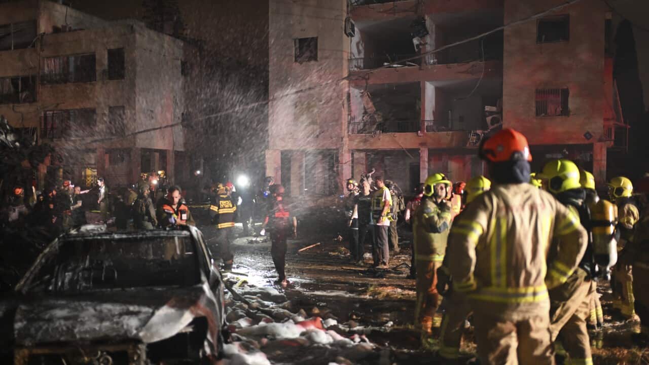 Firefighters spray foam over a burnt-out street.