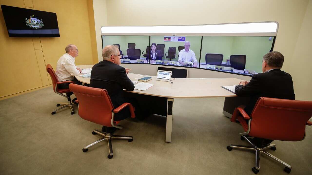 Prime Minister Scott Morrison and advisers speak to NSW Premier Gladys Berejiklian (on screen) during a National Cabinet meeting to discuss COVID-19